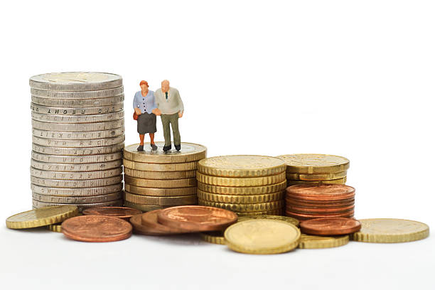 Senior couple standing next to a roll of American dollars. Retirement and pension theme