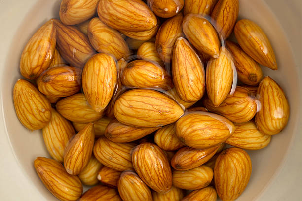 Closeup of almonds soaked in water Macro view of almonds sitting in a bowl of water, being soaked to make almond milk. drenched stock pictures, royalty-free photos & images