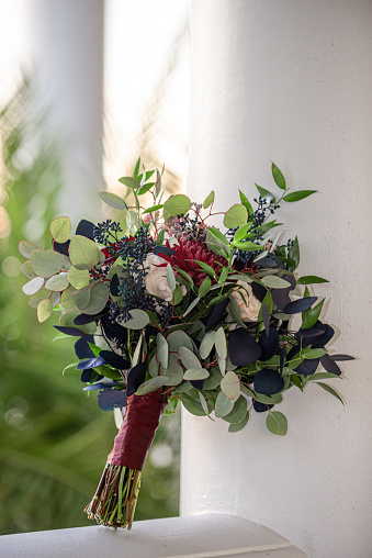 Standing red,pink and white bouquet with blue and green leaves outdoors on pedistal