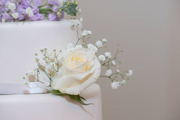 White layer wedding cake with purple and white flowers decorations close up