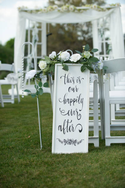 istock White sign that reads this is our happily ever afterat top of wedding ceremony isle with white chairs and white alter vertical 1788536607