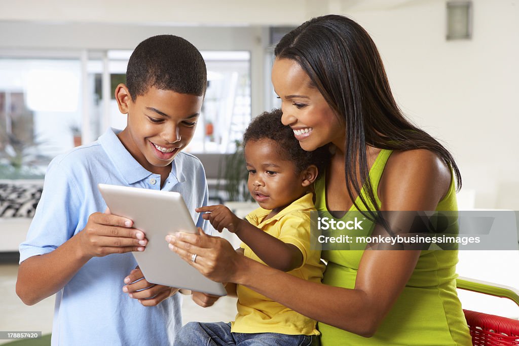 Mother And Children Using Digital Tablet In Kitchen Together Mother And Children Using Digital Tablet In Kitchen Together Pointing At Screen Smiling Toddler Stock Photo