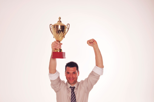 Successful businessman celebrating with the cup in hands.