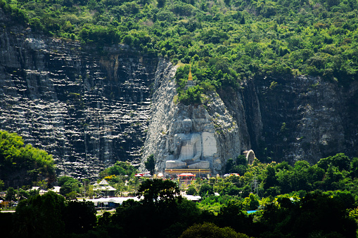 View landscape and sculpture carving big buddha carving on stone cliff mountain Wat Khao Tham Thiam for thai people travelers travel visit respect praying blessing at U Thong in Suphan Buri, Thailand