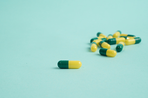 Medicine capsules scattered on blue background