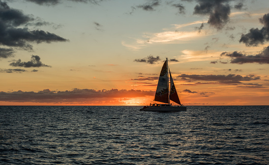 Beautiful sunset vista with a sailboat in the foreground off the coast of Honolulu on Oahu, Hawaii