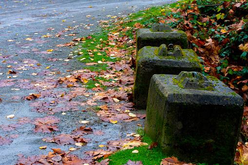 An image of three old moss covered concrete barricades blocking vehicle access to a drainage ditch.