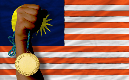 Winner holding gold medal for sport and national flag of malaysia