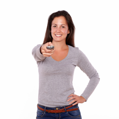 Portrait of a pretty lady pointing remote control while standing on white background