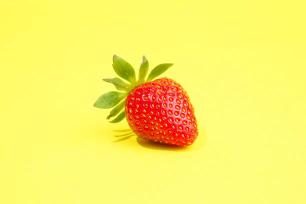Single strawberry isolated on yellow background