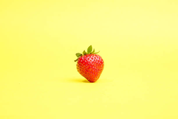 istock Single strawberry isolated on yellow background 1788663481