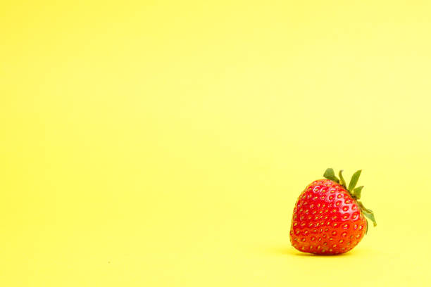 istock Single strawberry isolated on yellow background 1788663760