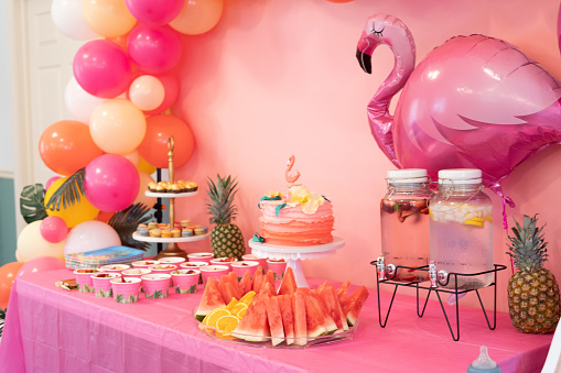 Hawaiian birthday theme. Birthday cake with Flamingo decoration. Table with sweets and drinks.
