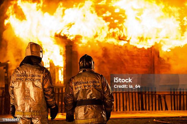 Firefighters At Burning Fire Flame On Wooden House Roof Stock Photo - Download Image Now