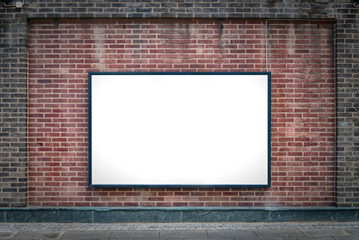 one blank billboard attached to a buildings exterior brick wall.