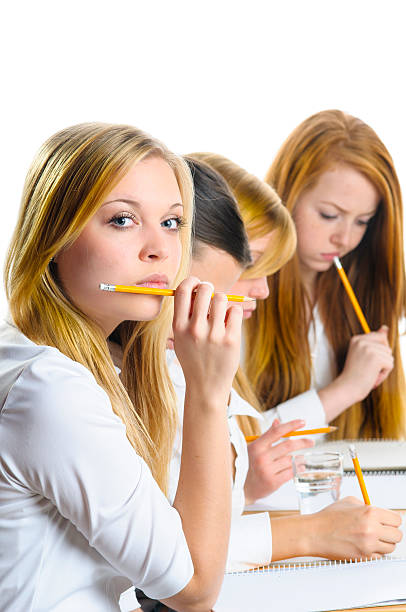 Two young focused student girls sitting in a library and studying together.