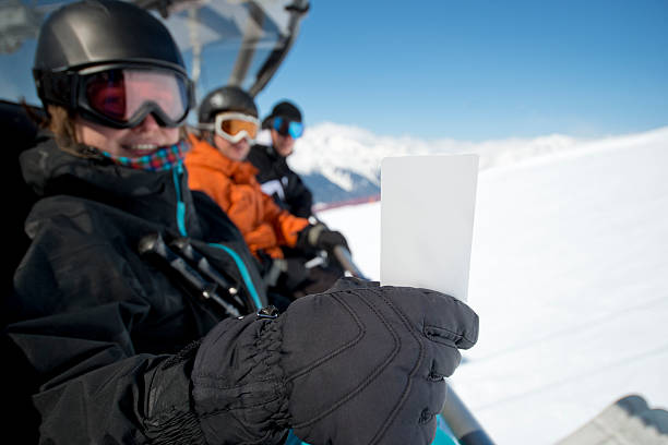 Winter sport friends in chair lift with ticket stock photo