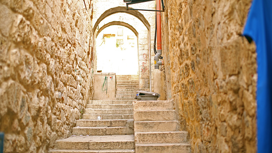 Looking up an empty Jerusalem laneway with light bursting through at the top