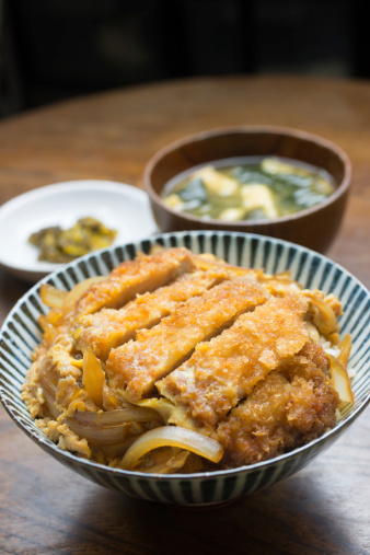 A katsudon (カツ丼) is a popular Japanese food, a bowl of rice topped with a deep-fried pork cutlet(豚カツ), egg, and condiments.