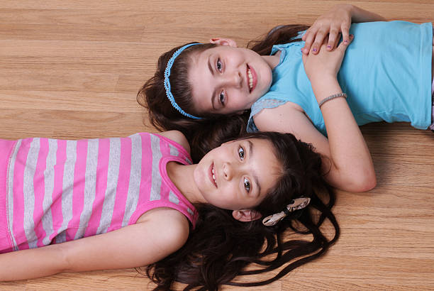 istock Two smiling girls lying on the ground together 178875626