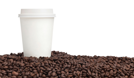 A horizontal shot of a blank coffee cup on a pile of coffee beans isolated on white.