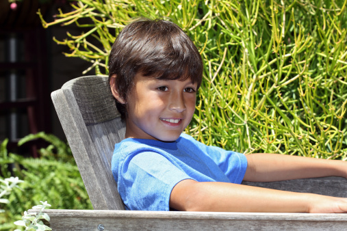 Young boy smiles as he relaxes on a park bench