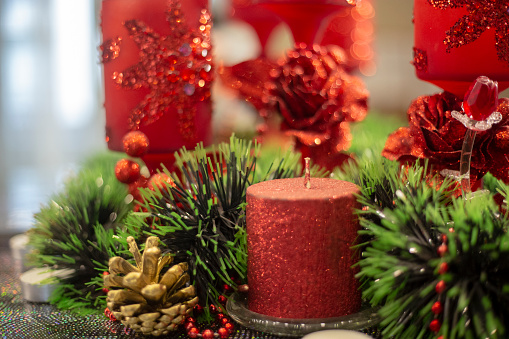 Christmas decorations. Candles in glass jars with fir on holiday background. Cozy handmade holiday home decor: glass jar with candle decorated with red ribbon.