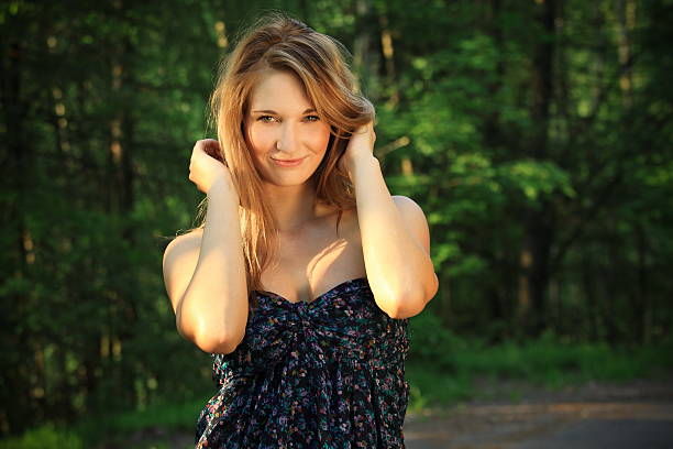 Beautiful blonde girl posing in nature, in the background are trees and greenery, fashion photography