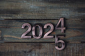 Concept of change 2024 to 2025. Christmas or New Year minimalistic composition. Holidays card on wooden background, zero waste decorations. Sustainable lifestyle, natural elements
