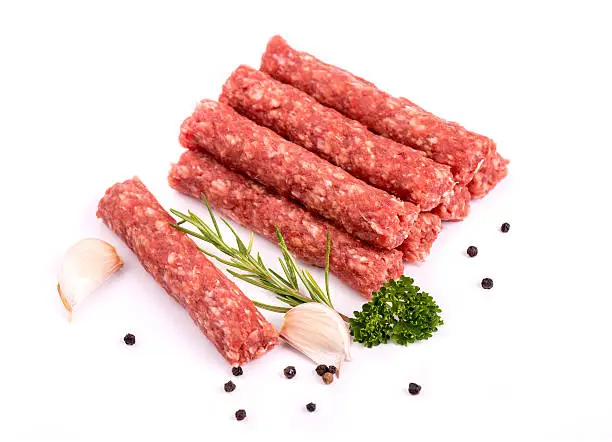 Delicious meat cevapcici with pepper, rosemary, parsley and garlic, isolated on white