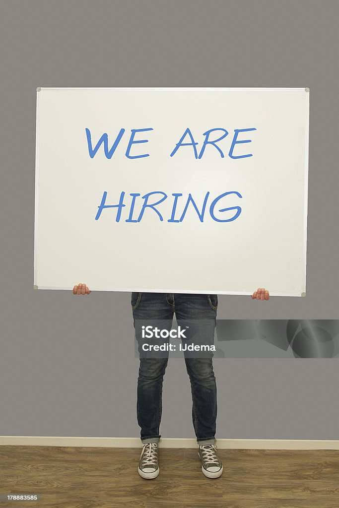 Woman holding we are hiring sign Woman holding a big whiteboard with we are hiring written on it We are Hiring Stock Photo