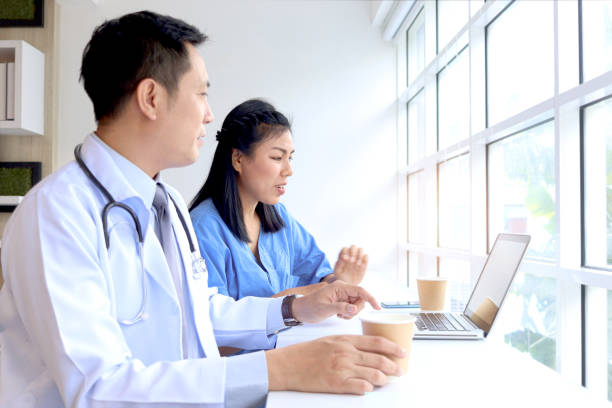 istock Happy smiling Asian female doctor taking break, drinking coffee during talking with teammate. Relaxed carefree medical staff sitting in hospital cafe. Professional medical team chatting during a break 1788854037