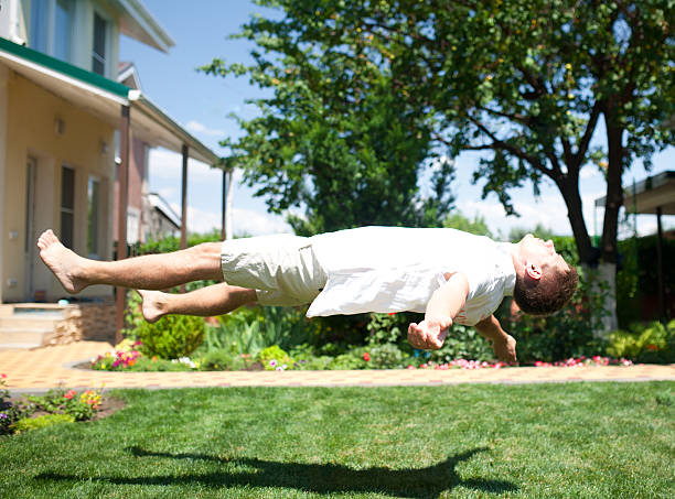 giovane uomo volare o levitating sull'erba nel cortile dietro casa - flores man foto e immagini stock
