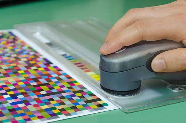 Photo of human hand, spectrophotometer measures color patches for profile creation