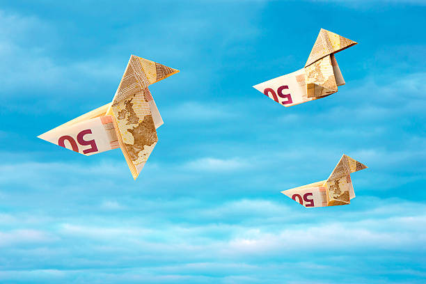 Bank note paper birds flying away on blue sky