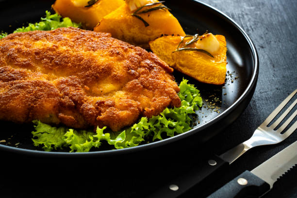 istock Breaded fried pork chop with baked pumpkin on wooden table 1788920002