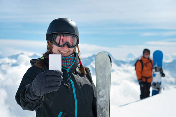 Girl holding blank ski ticket smiling stock photo