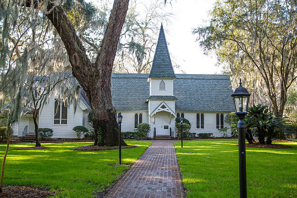 Small Church Past Brick Walk and Green Lawn Horizontal Small White Church Under Moss Covered Trees baptist stock pictures, royalty-free photos & images
