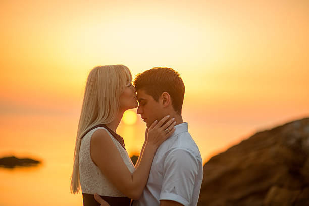 couple kissing on the beach at sunrise - teenager couple child blond hair стоковые фото и изображения