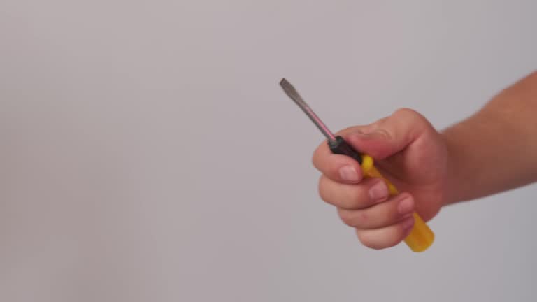 Close up, male hand holding and rotate yellow screwdriver on light background