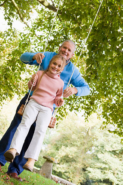 istock Grandfather pushing granddaughter on swing 178893977