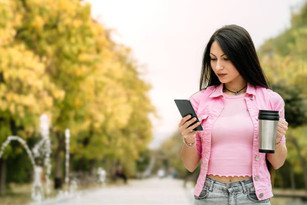 istock Young woman drinking coffee and using phone at the park 1788941208
