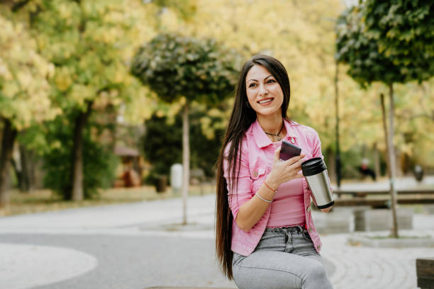 istock Young woman drinking coffee and using phone at the park 1788941519