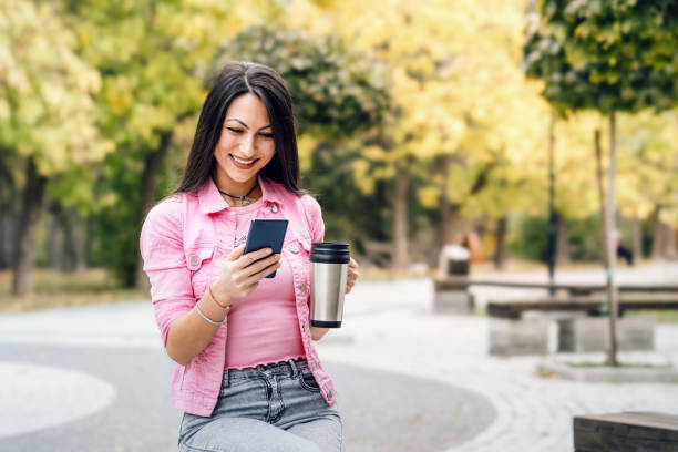 istock Young woman drinking coffee and using phone at the park 1788941718