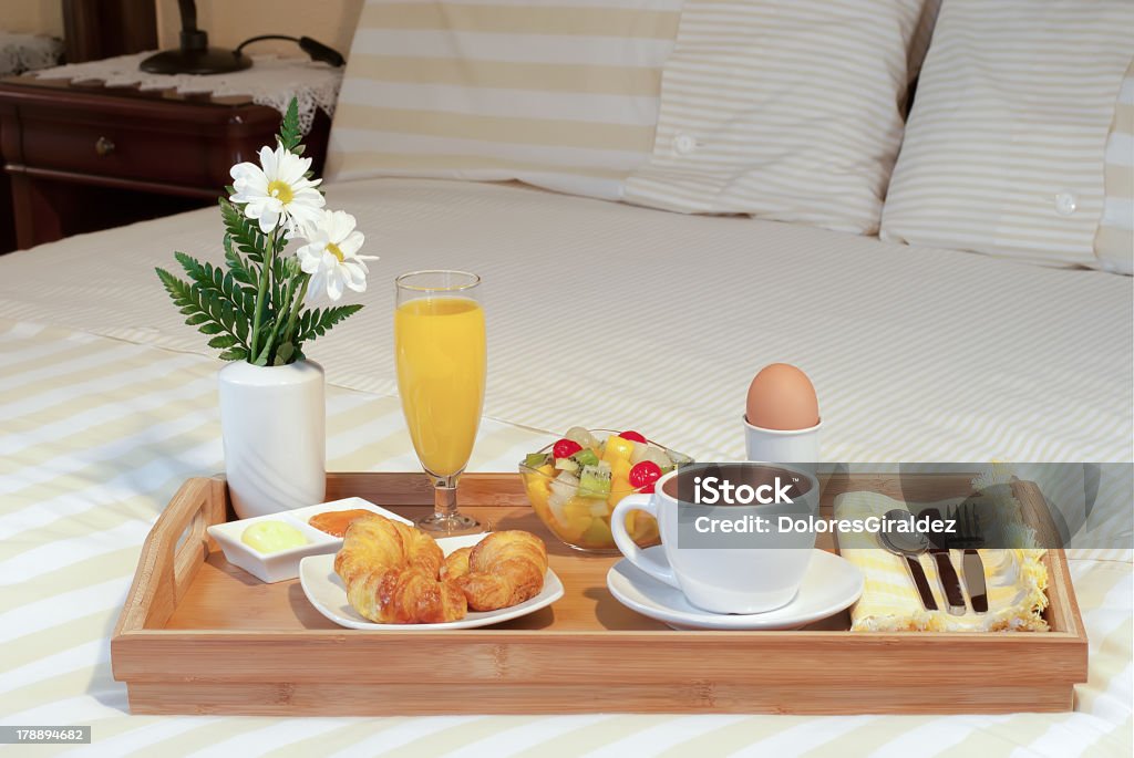 Breakfast tray in bed Breakfast tray in bed with flowers with croissant, orange juice, eggs and fruit salad Bed - Furniture Stock Photo