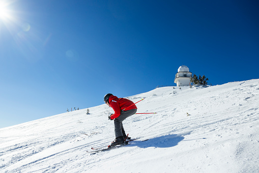 Young skier downhill skiing at Jahorina ski resort, Bosnia and Herzegovina, in winter afternoon.