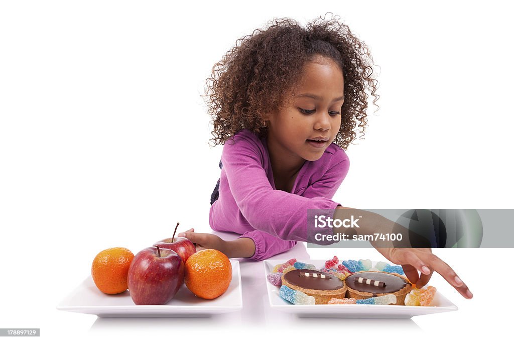 Piccola ragazza asiatica africana esitazione tra frutta o dolciumi - Foto stock royalty-free di Afro-americano