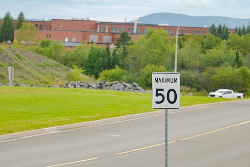 speed limit signboard on the road car in the background