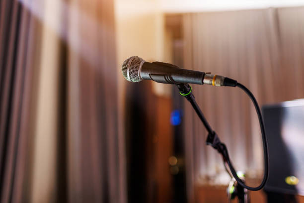 istock Microphone on stand on stage close up with searchlight light. Professional mic at concert hall or conference room, karaoke, night club, bar. Public events, festival, wedding. Copy space. 1788995774
