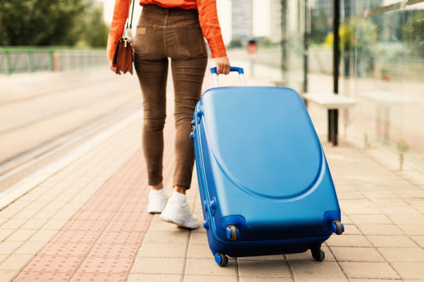 colpo ritagliato di una turista signora che cammina con una valigia da viaggio all'aperto - bus rear view white commercial airplane foto e immagini stock